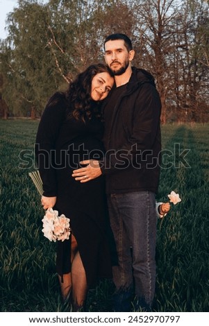 Young pregnant couple taking pictures on the outdoor at sunset hugging each other feeling happy. Lifestyle