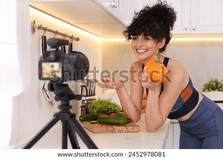 Smiling food blogger explaining something while recording video in kitchen Royalty-Free Stock Photo #2452978081