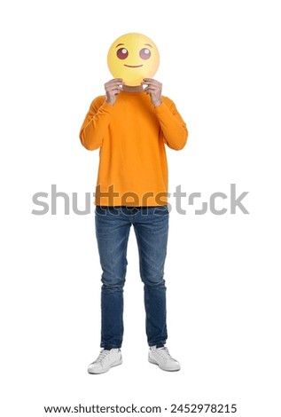 Man covering face with smiling emoticon on white background