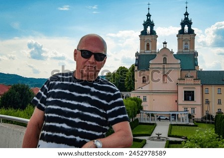 Bold man in summer sunglasses at chapel castle travel destination. Summer castle and man. Banner.