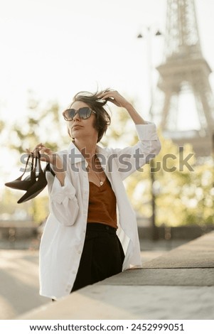 beautiful girl near the eiffel tower in the background with shoes in hand