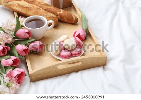 Delicious breakfast and flowers on bed. Space for text