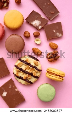 Pastel macarons, almond chocolate, peanut butter cookies and various nuts on bright pink background. Top view.