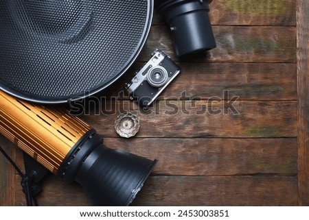 Photo studio equipment concept top view background with copy space. Photostudio led constant light sources and different light modifiers on the wooden table background. Royalty-Free Stock Photo #2453003851