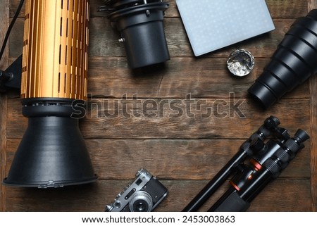 Photo studio equipment concept top view background with copy space. Photostudio led constant light sources and different light modifiers on the wooden table background. Royalty-Free Stock Photo #2453003863