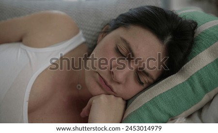 Stressed 30s woman close-up face laid on couch frowning putting hands in forehead struggles with life's challenges and headache Royalty-Free Stock Photo #2453014979