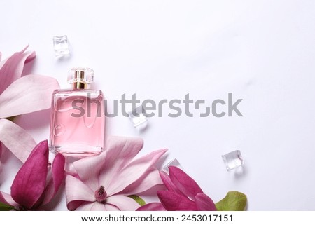 Beautiful pink magnolia flowers, bottle of perfume and ice cubes on white background, flat lay. Space for text