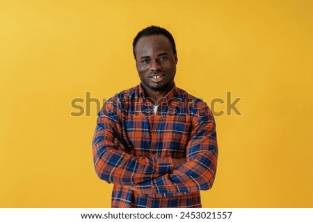 Standing and posing. Black man is in the studio against yellow background.