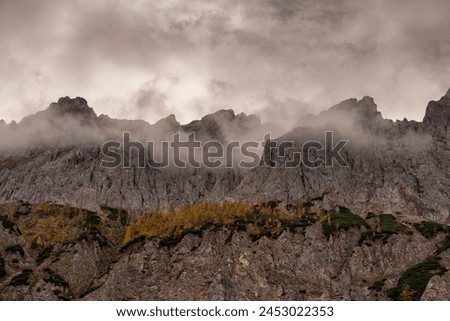 Rain clouds forming around a menacing set of mountain peaks with golden larch forests, Hochschwab mountains, Steiermark (Styria), Austria Royalty-Free Stock Photo #2453022353