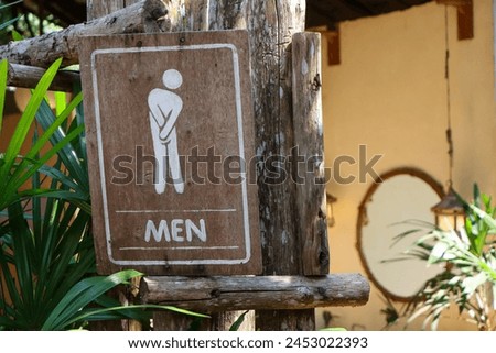 Selective focus: Men's restroom sign decorated with shady trees in front of a restroom in a cafe in the forest in Thailand.