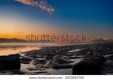 Draining water and a beautiful sunrise with fog on the Weser beach in Berne, Julis Plate.