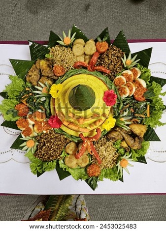 Tumpeng or tumpeng rice is a dish served at traditional ceremonies in Javanese, Balinese, and Sundanese communities where the rice is served in a cone shape and arranged together with theside dishes. Royalty-Free Stock Photo #2453025483