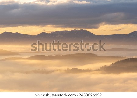 Tiny village of Hörzendorf nestled between the Karawanken mountains, covered in thick fog at sunrise, Carinthia, Austria Royalty-Free Stock Photo #2453026159