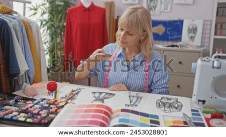 A focused caucasian woman reviews fashion designs in a well-equipped tailor shop with colorful fabric swatches