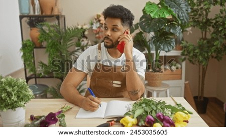 An african american man in a florist shop talking on the phone while taking notes surrounded by plants.