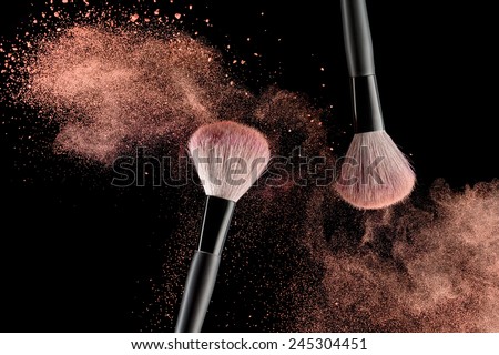 Make-up brush with pink powder explosion on black background Royalty-Free Stock Photo #245304451