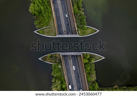 Top down aerial of highway with traffic passing underneath Veluwemeer aquaduct. Dutch waterway infrastructure for boats to pass over freeway seen from above. 