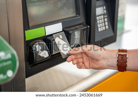 Close up view of man hand pays for fuel with a credit card on terminal of self-service filling station in Europe. High quality photo