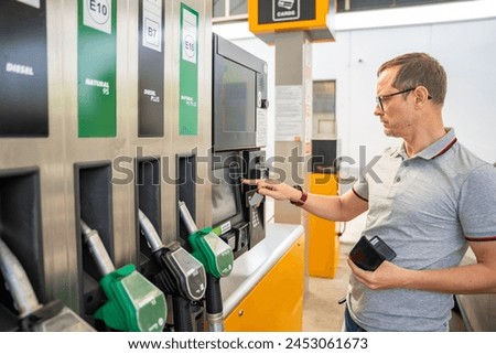 The man pays for fuel with a credit card on terminal of self-service filling station in Europe. High quality photo
