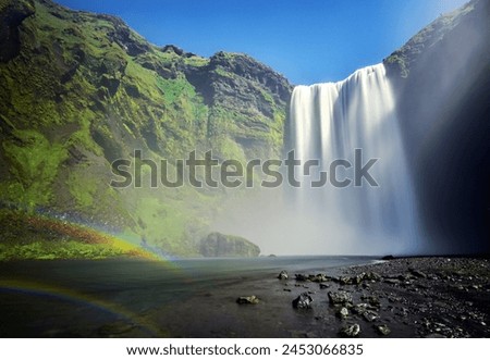 A waterfall with a rainbow in the background
