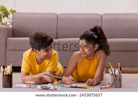 Boy and girl drawing while lying down on floor in at home
