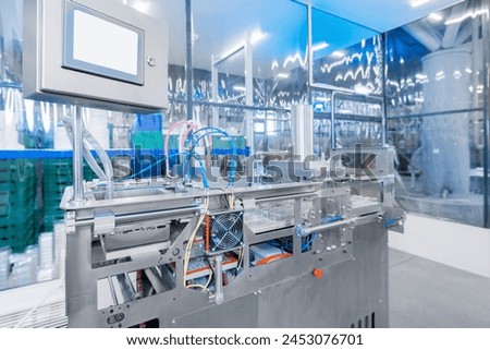 Operation of automatic machine plastic form for kit medical production. Closeup of roller blue toning, with sun lighting effect. Royalty-Free Stock Photo #2453076701