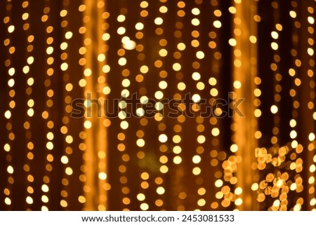 Abstract bokeh effect of the gold, yellow lights on black background. City street light decorations. Rows of LED gold colored light spots with black background. 