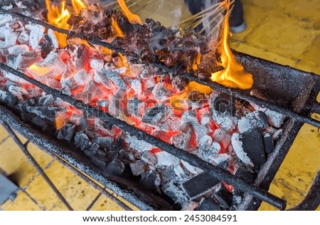 Several skewers of beef being grilled on the grill, with the fire burning, stock photo.