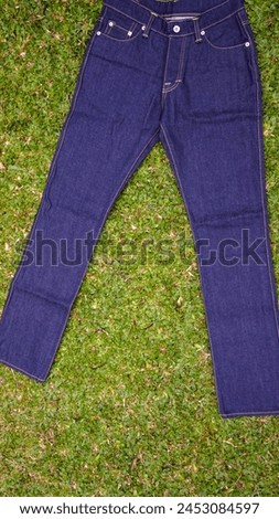 Indigo colored jeans pants, with grass background, stock photo.