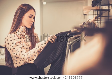 Young woman choosing clothes on a rack in a showroom  Royalty-Free Stock Photo #245308777