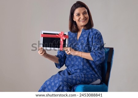 Happy Indian lady showing her new gift tablet