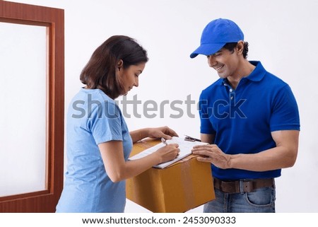 Smart Indian woman signing a home delivery receipt of a package at the time of delivery