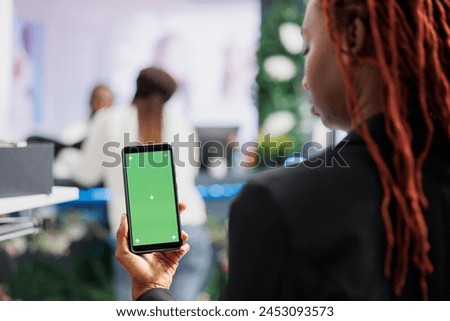African american woman using smartphone with green screen while shopping for clothes in mall. Boutique buyer holding mobile phone with empty chroma key display for copy space