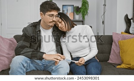 Affectionate couple sitting on sofa at home, sharing a quiet moment with a pregnancy test in hand, reflecting anticipation and support