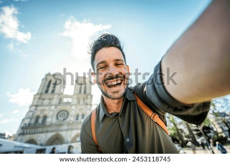 Handsome man taking selfie with smart mobile phone device on city street - Happy tourist visiting Notre Dame in Paris, France - Summer holidays and travel influencer concept