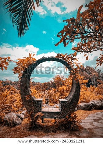 The photo spot consists of a seat made of rattan surrounded by plants and flowers
