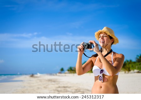 Joyful woman taking photo at tropical caribbean beach during summer vacation. Happy brunette having fun in Playa Paraiso, Riviera Maya, Mexico.