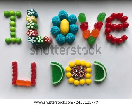 Photo of a message to a father, created with assorted bright colorful candies saying, "I love you dad!"