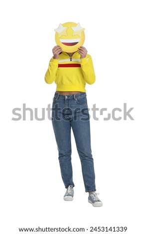 Woman holding emoticon with stars instead of eyes on white background
