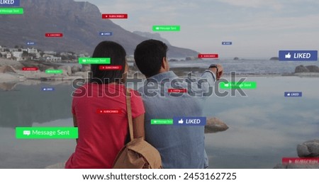 Image of social media text and icons over biracial couple on beach. Global social media, digital interface, computing and data processing concept digitally generated image.