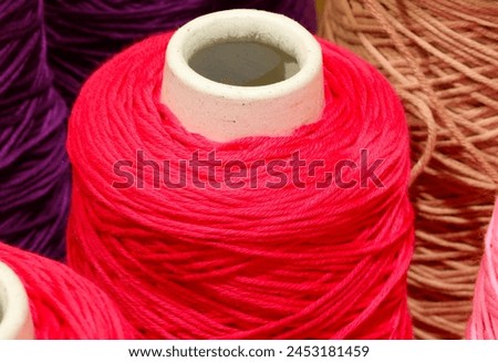 ball of wrapped red thread and other colors in the warehouse of the artisan knitting factory Royalty-Free Stock Photo #2453181459