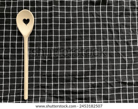 Wooden decorative spoon on the table, from heart, on checkered background