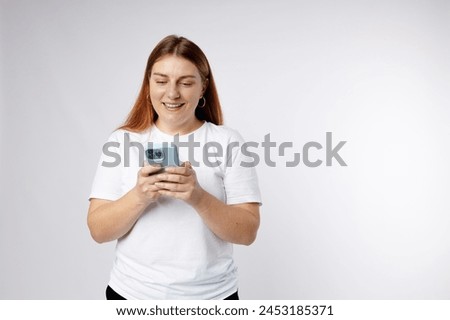 Smiling young brunette woman with smart phone posing isolated on white background, studio portrait. Cute beautiful 30s woman chatting by mobile phone
