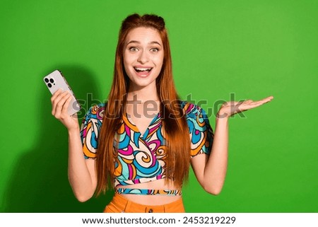 Photo portrait of attractive woman hold device palm shocked empty space dressed stylish retro clothes isolated on green color background