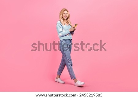 Full size photo of lovely young woman hold device walking dressed stylish flower print garment isolated on pink color background