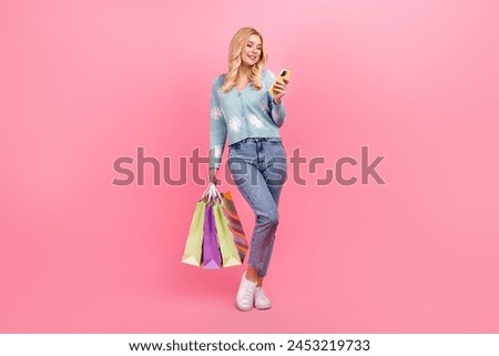 Full size photo of lovely young woman hold shopping bags device dressed stylish flower print garment isolated on pink color background
