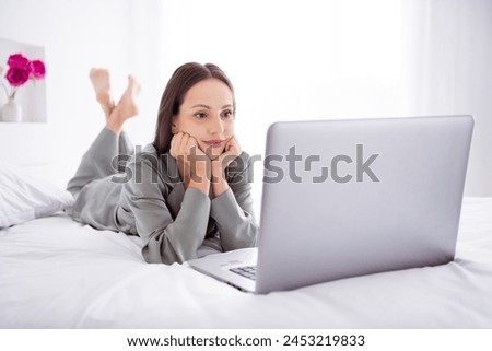 Photo of cheerful charming lady wear grey pajama enjoy weekend watching movie modern device indoors house bedroom