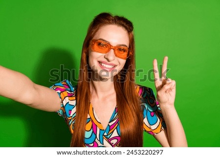 Photo portrait of attractive young woman sunglass selfie photo v-sign dressed stylish retro clothes isolated on green color background