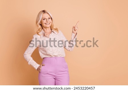 Photo portrait of nice retired female posing boss point empty space wear trendy formalwear isolated on beige color background