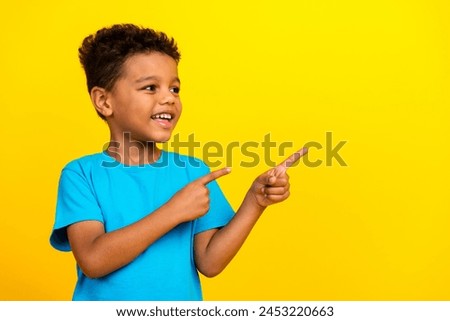 Portrait of mixed race multiethnic multinational schoolboy look directing at discount empty space isolated on vivid yellow background Royalty-Free Stock Photo #2453220663